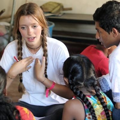 A Projects Abroad volunteer doing childcare work in Sri Lanka with a group, leads a discussion with young children. A volunteer doing community work in Sri Lanka with a group, teaches young children English phrases.